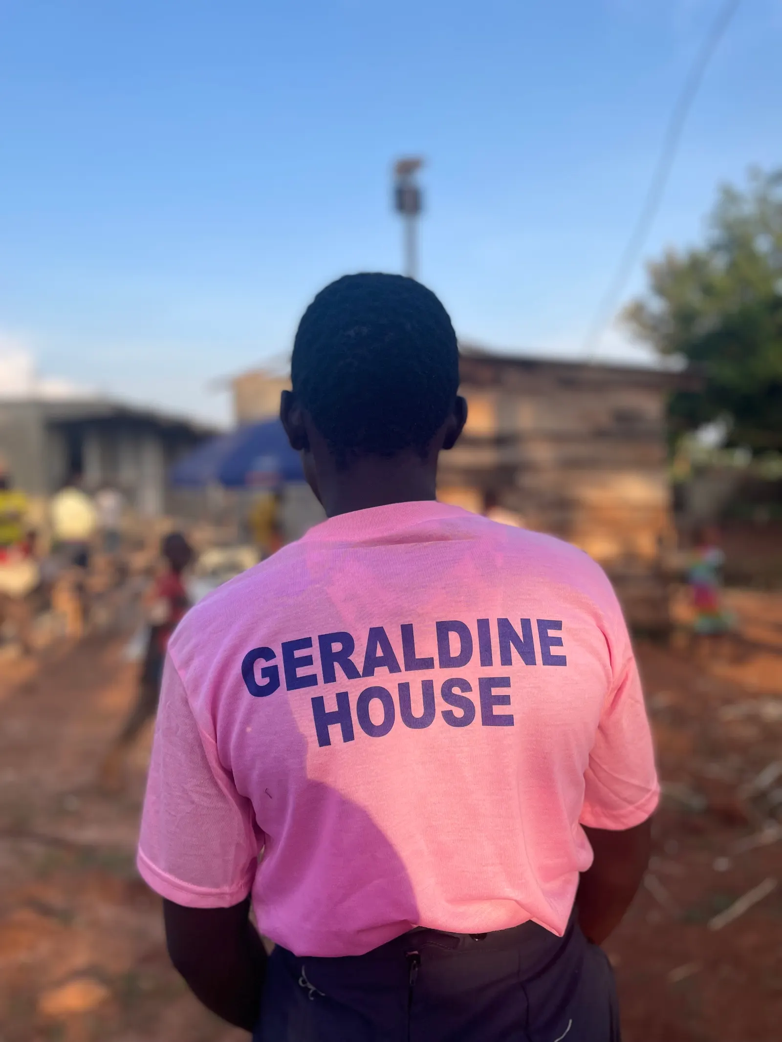 Student seen from behind wearing a pink Geraldine House t-shirt on the school grounds