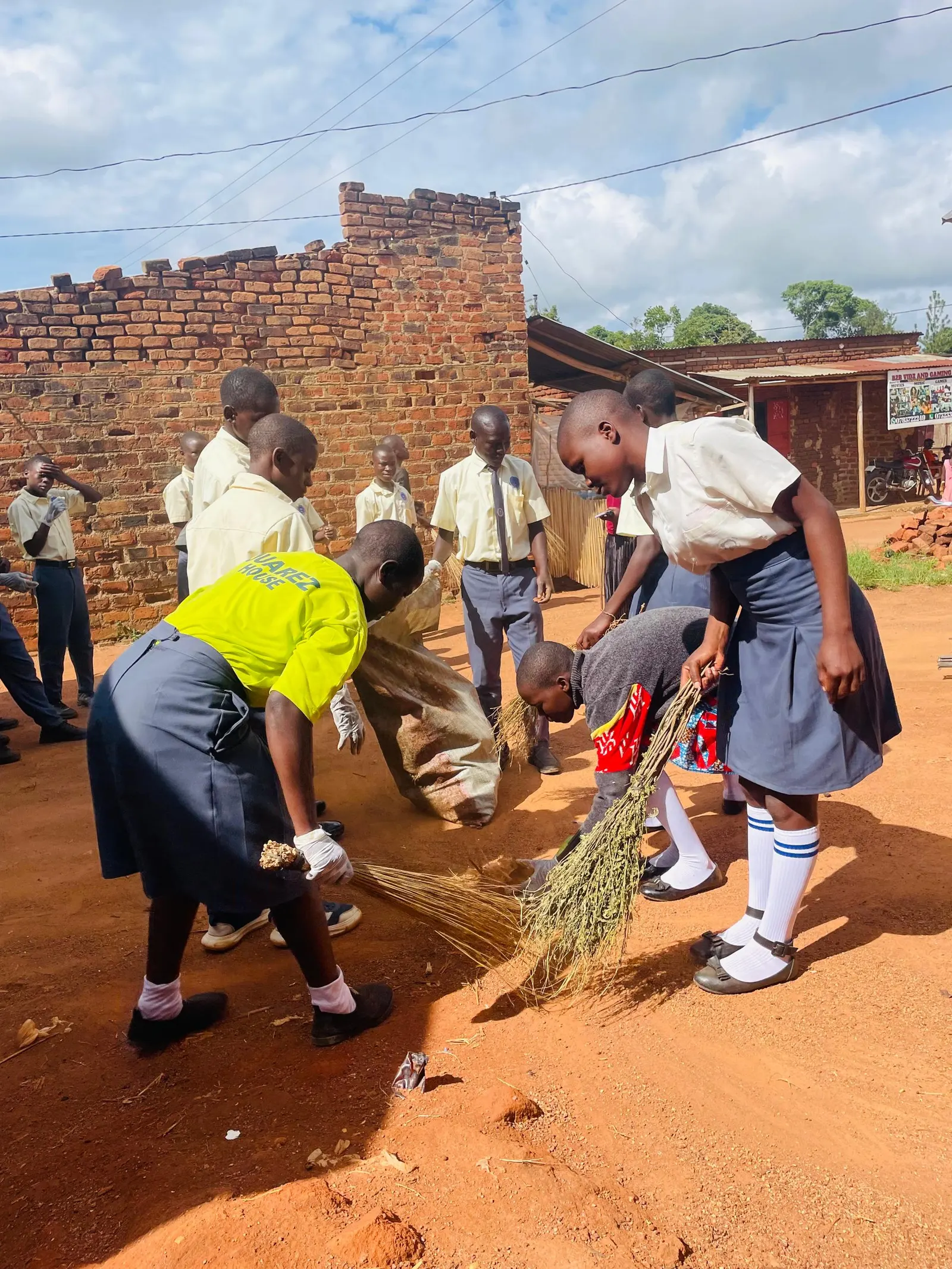 Students in yellow shirts sweep the compound before class