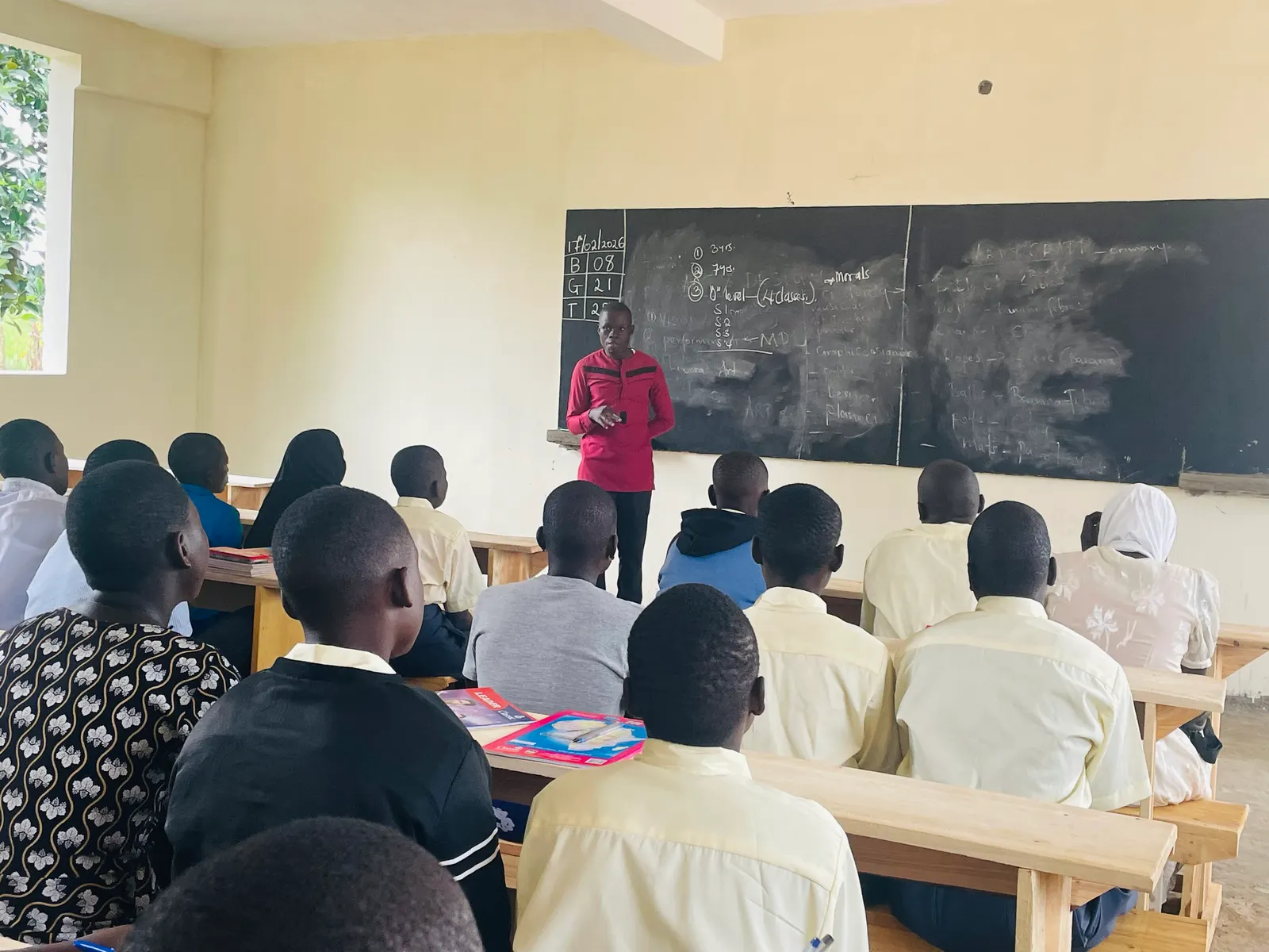 A teacher writes on the blackboard while students watch from their desks